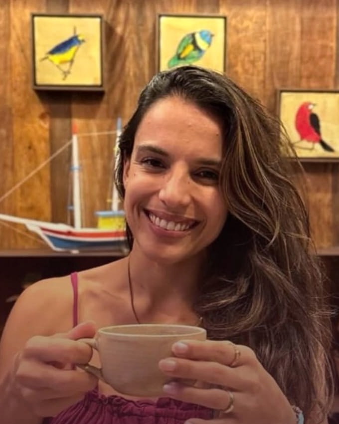 Luciana Gomes, nutricionista, sorrindo com uma caneca nas mãos